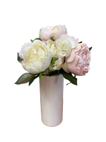 Bouquet of pink and white flowers in a white vase on a wooden surface with a gray background
