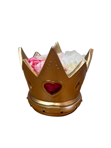 Gold crown-shaped container with flowers on a wooden surface