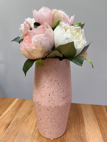 Pink speckled vase with pink and white flowers on a wooden surface